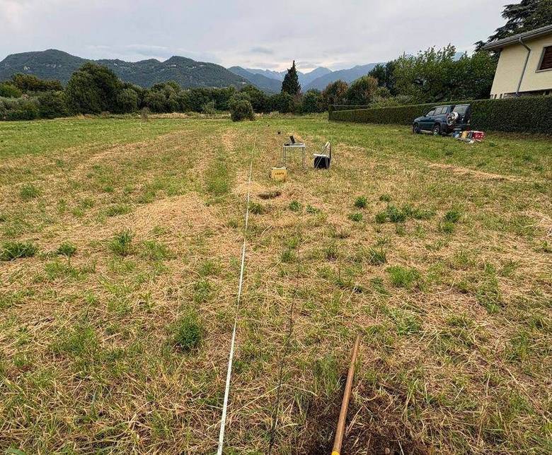 Profilo sismico con geofoni in un campo, con montagne sullo sfondo